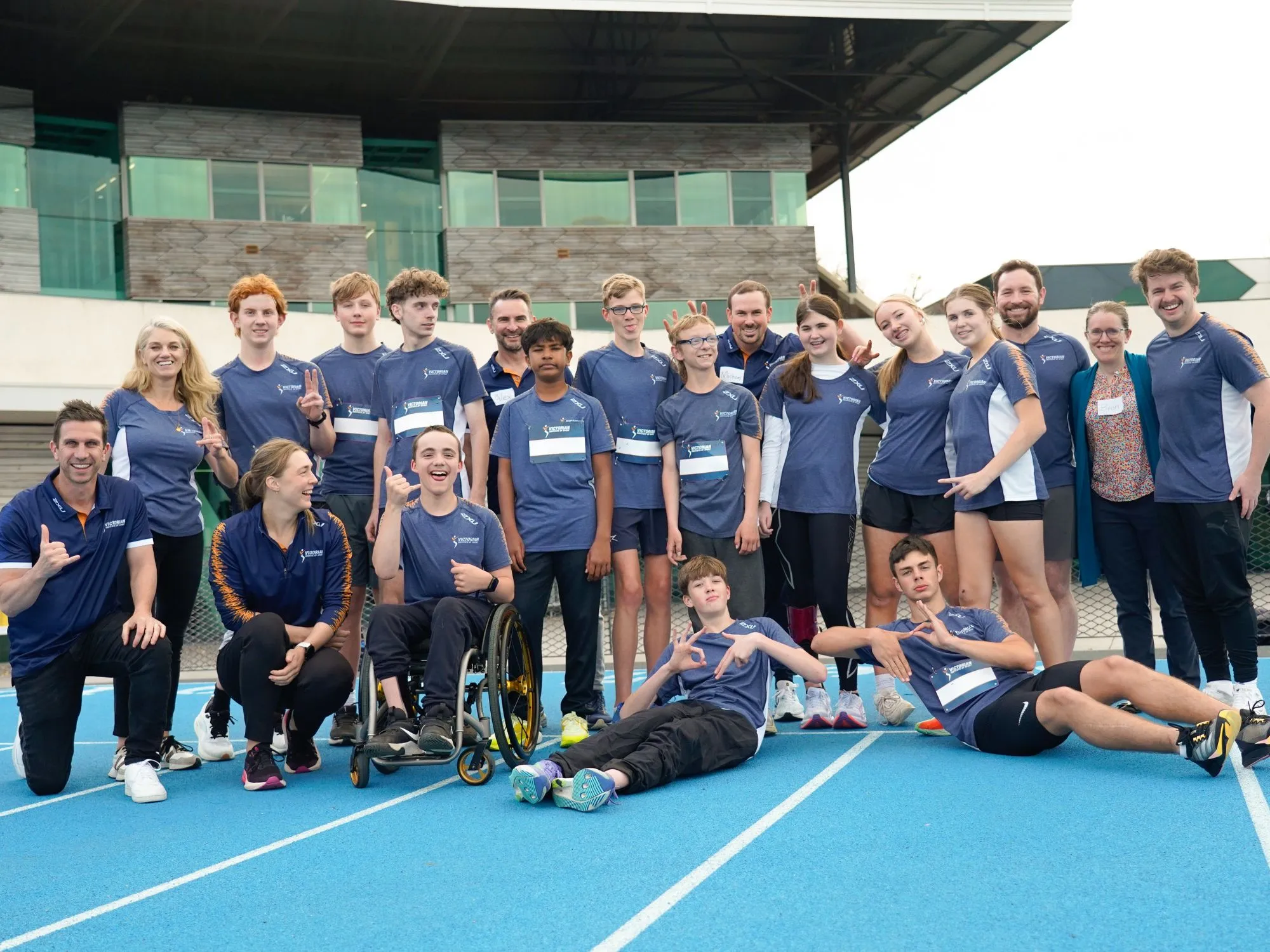 A large group of athletes all under 18 years of age, wearing VIS uniform smiling at the camera.