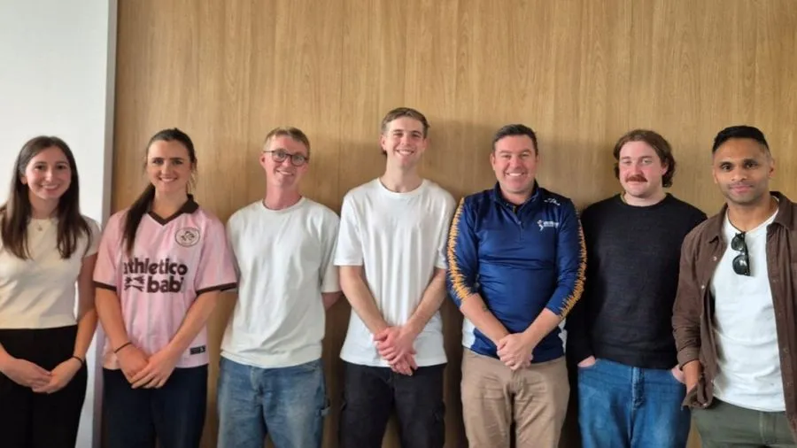 A group photo of 7 people standing side by side, a blend of university students and working professionals.
