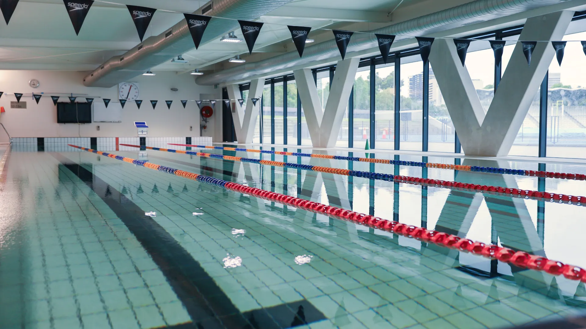 A photo of a 25-metre indoor lap pool with lane roles and flags.