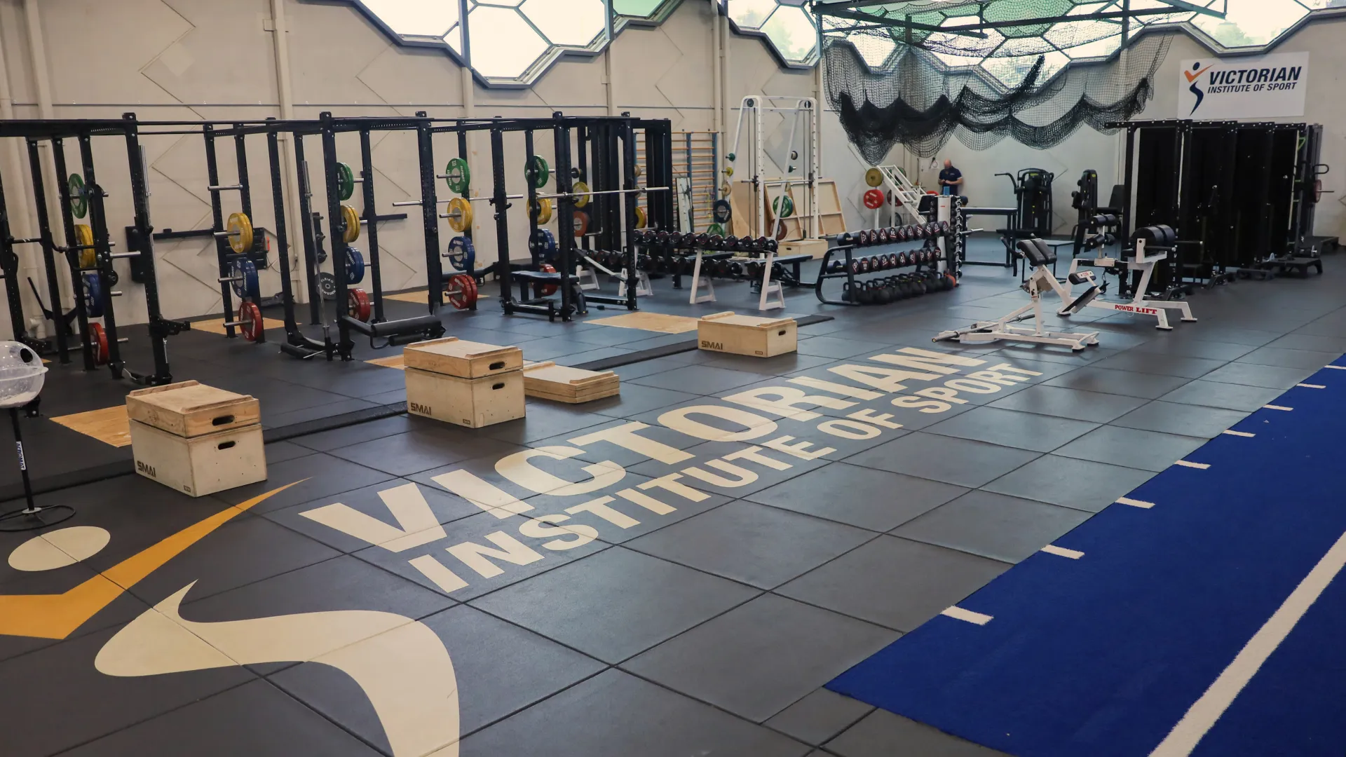 A photo of an indoor gym with numerous exercise equipment and the Victorian Institute of Sport logo painted on the floor. 