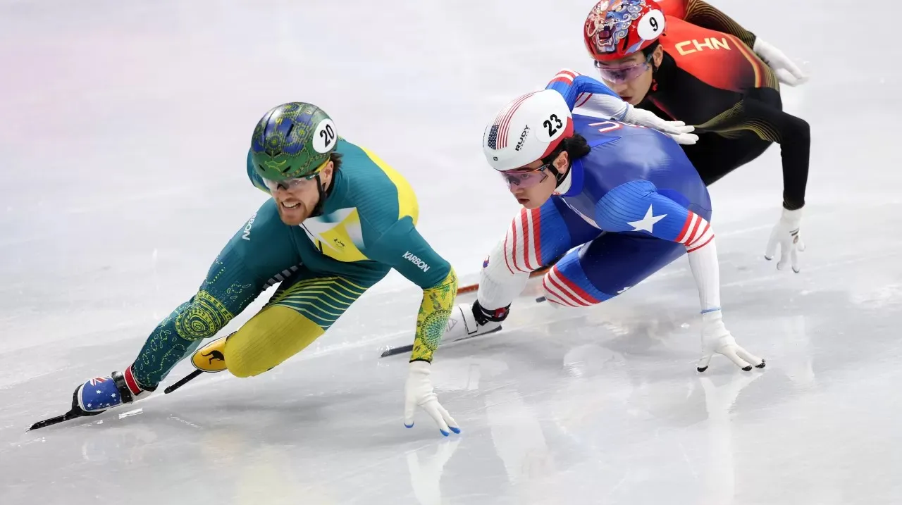 Three male speed skating athletes are wearing lyrca and racing on ice.