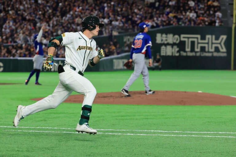 Baseball player in white Australia uniform running stance moving between bases.
