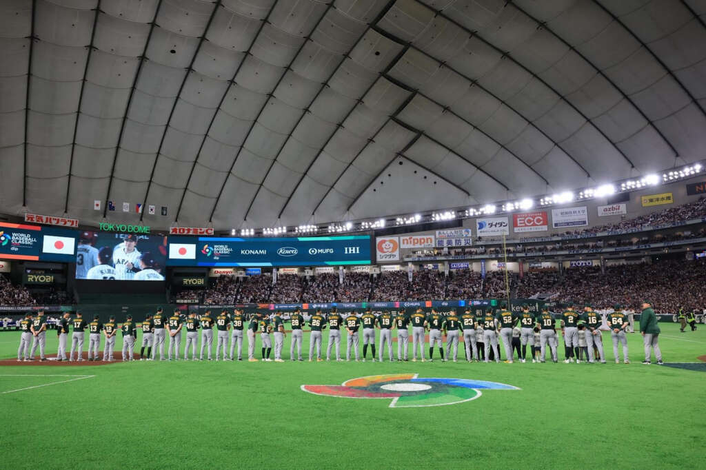 Team Australia for baseball line up on a green baseball field indoors.