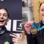 Two women hold gold medals up and are smiling celebrating their wins