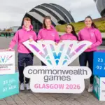 Four individuals in pink smiling for the camera in front of a sign.